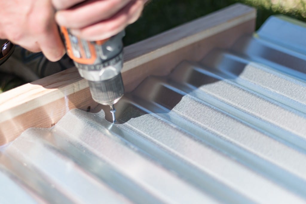 Screwing the corrugated metal panels into place