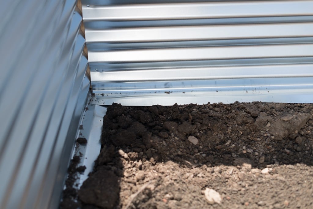 Peering inside the raised metal garden bed and evaluating workmanship