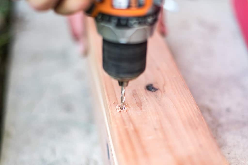 Predrilling the redwood to reduce the chance of splitting the wood