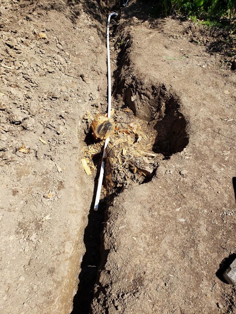 Digging trenches for irrigation pvc pipes beneath the raised beds