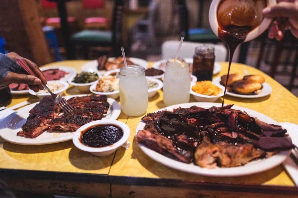 Oakland food scene everett and jones barbeque pouring sauce