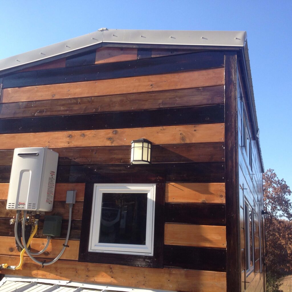 Tankless rinnai water heater mounted on the outside of our tiny home.