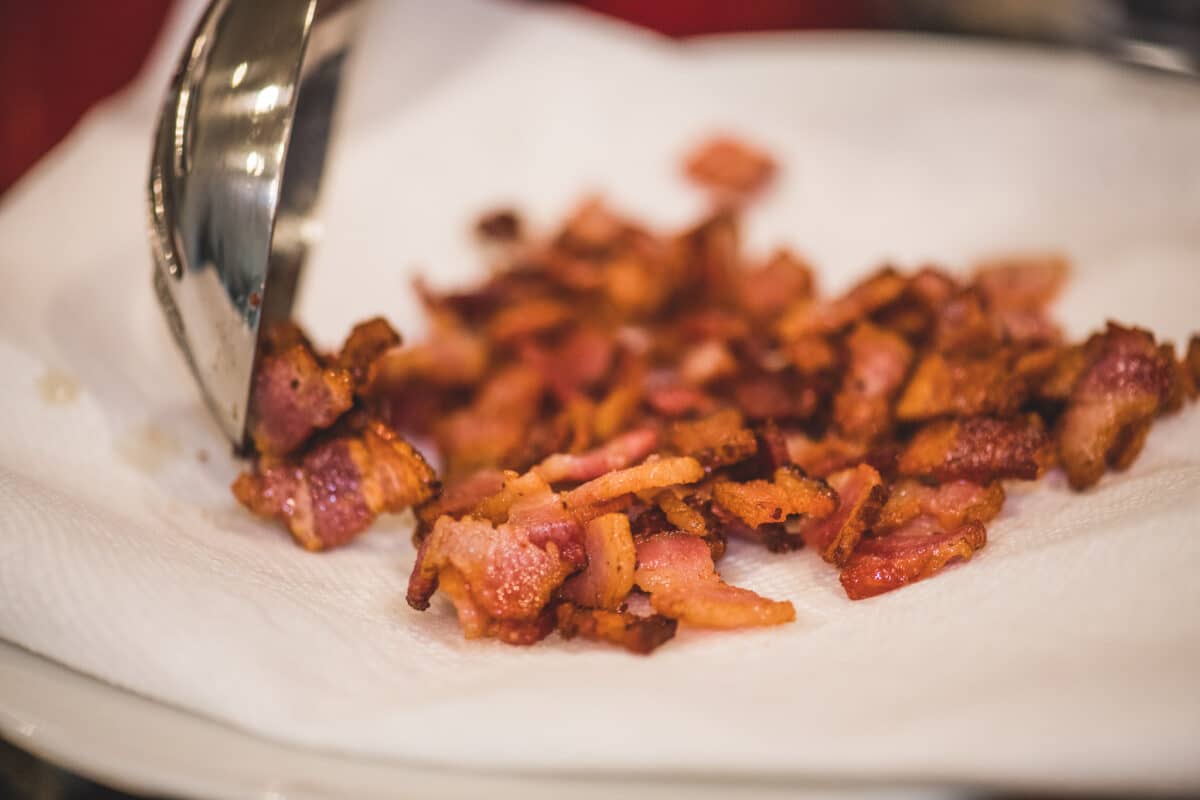 Transferring cooked bacon to a paper towel lined plate