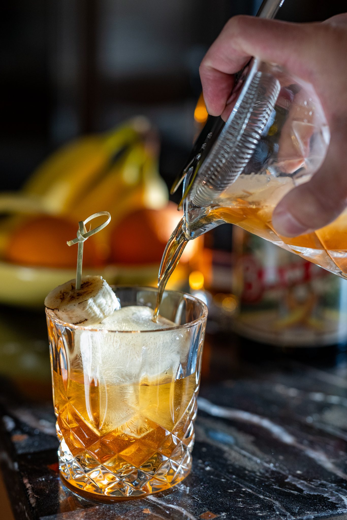 Banana old fashioned cocktail pouring into glass