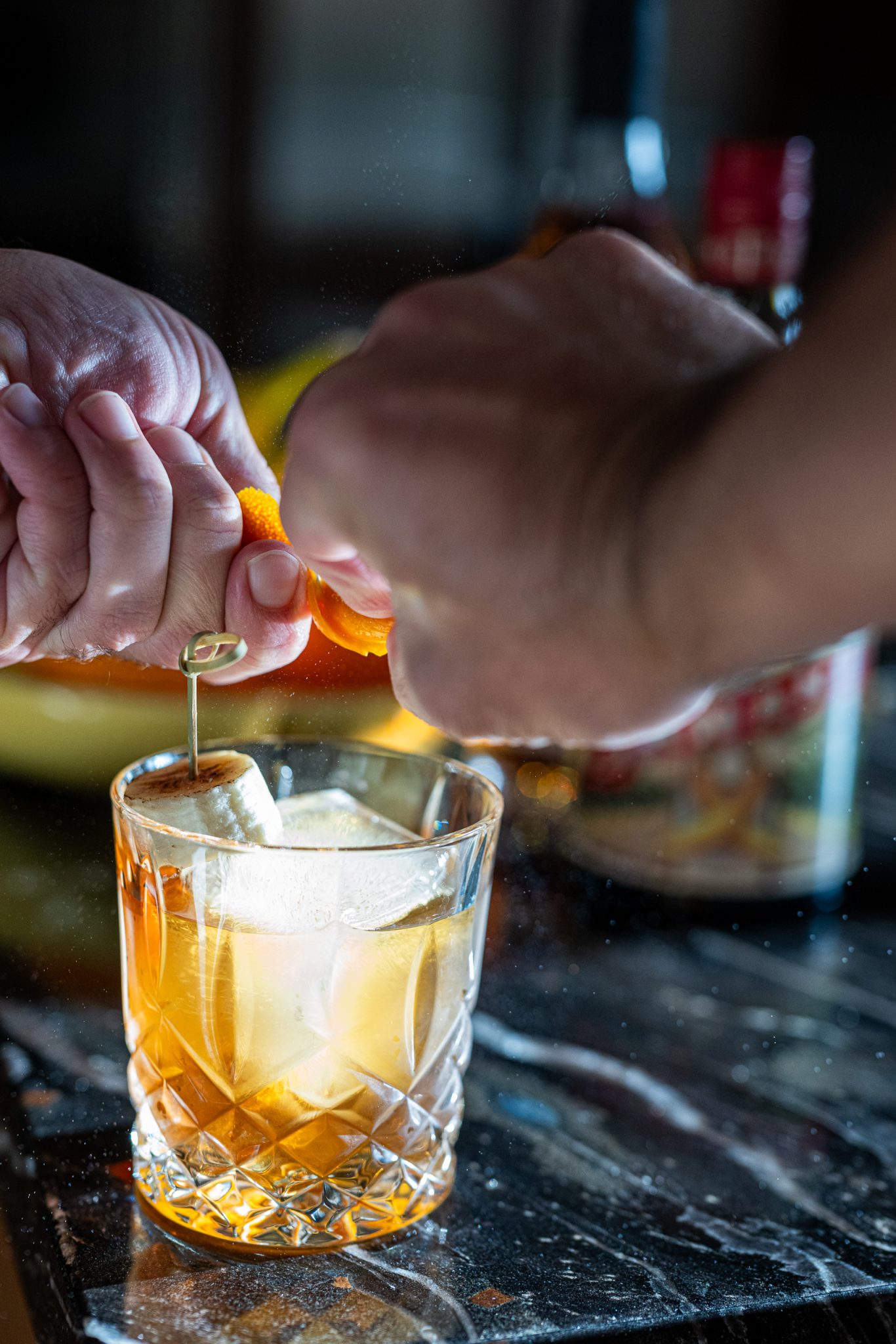 Banana old fashioned cocktail squeezing orange peel