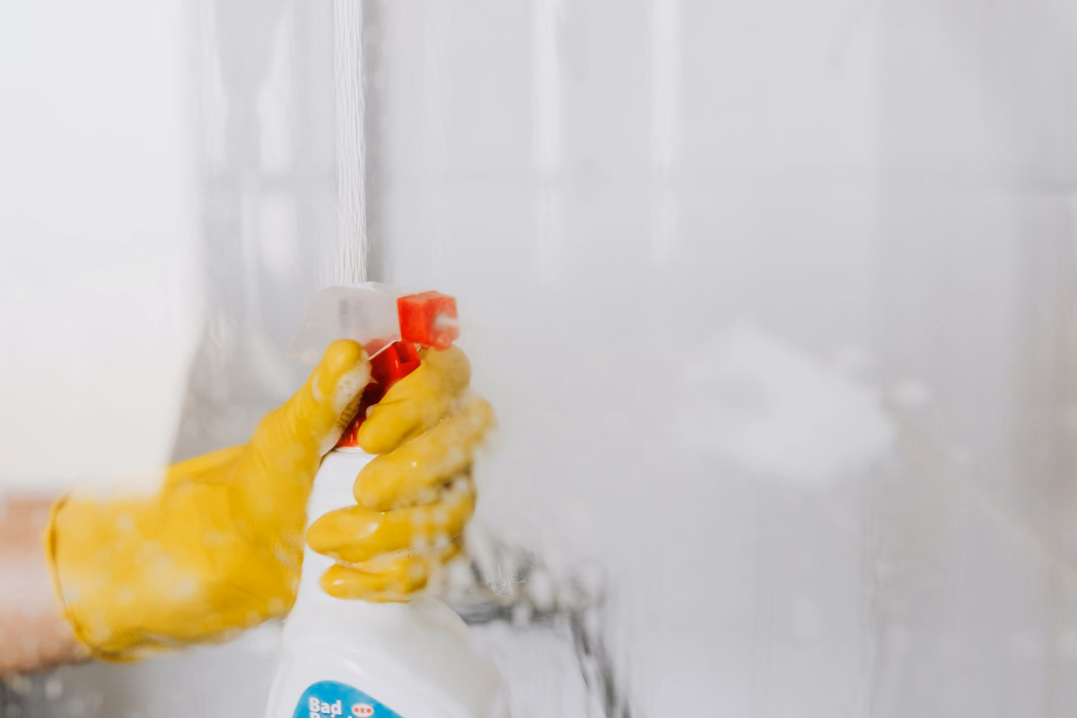 Person spraying non-toxic cleaner on shower glass