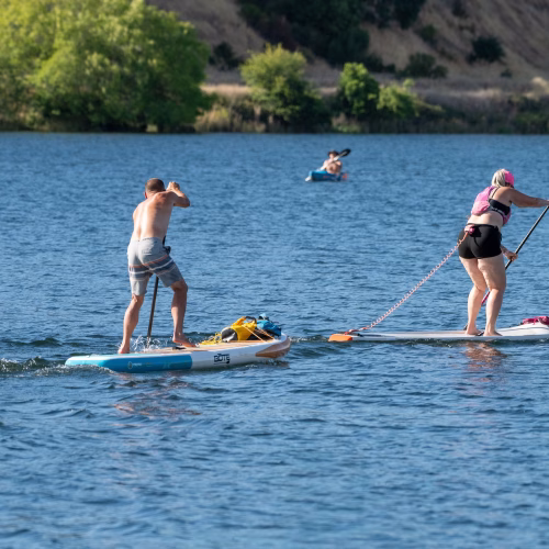 Two paddle boarders and a kayaker on lake natoma during a summer time trial session
