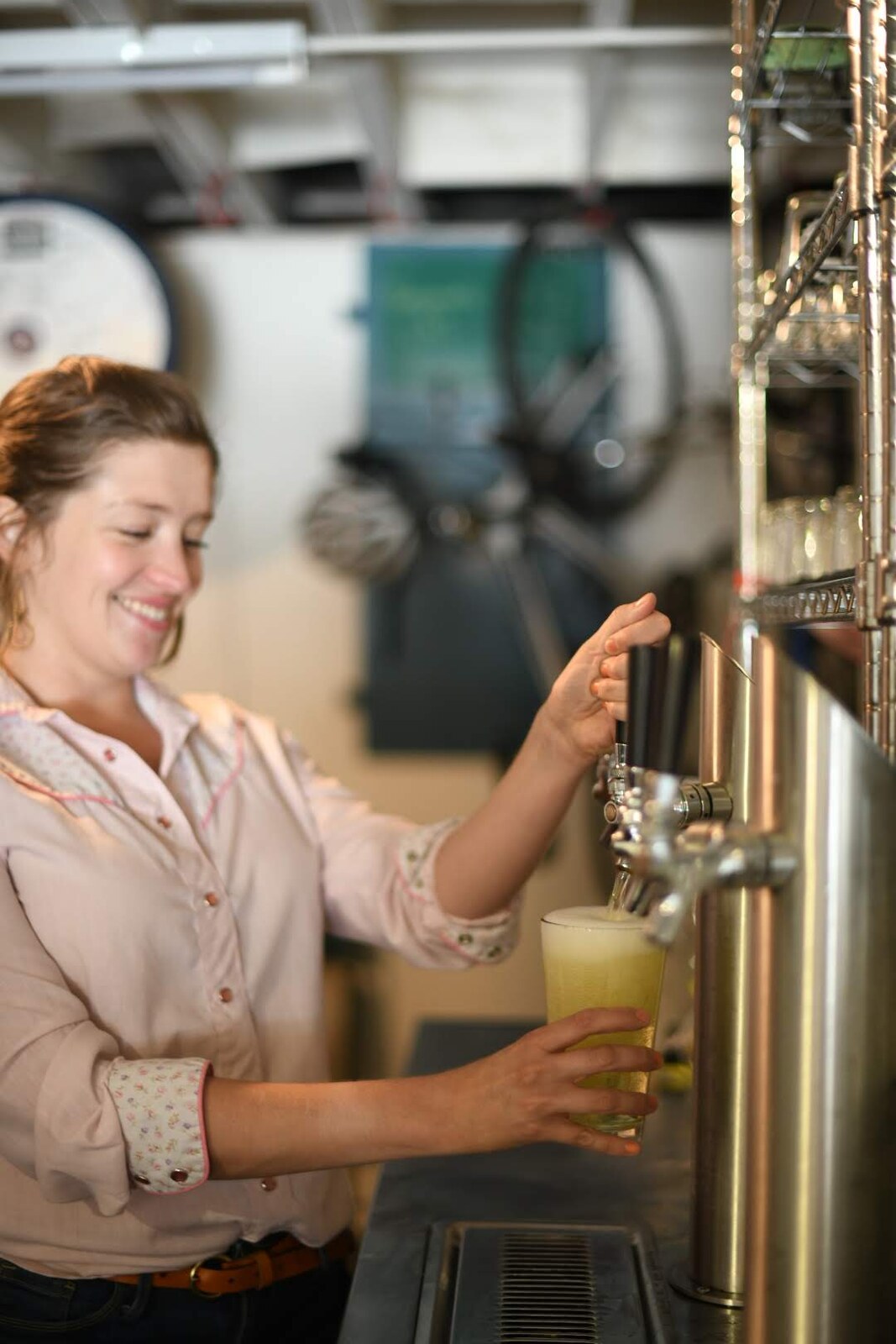 Bartender pours a beer at the taps with a bicycle visible behind the bar at a sacramento brewery