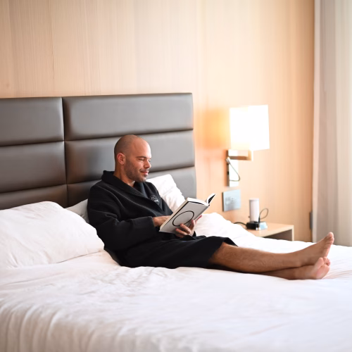 Michael kahn in a hotel robe, sitting up in bed reading a book, the same kind of sick-day research session that produced this probiotic-antibiotic guide
