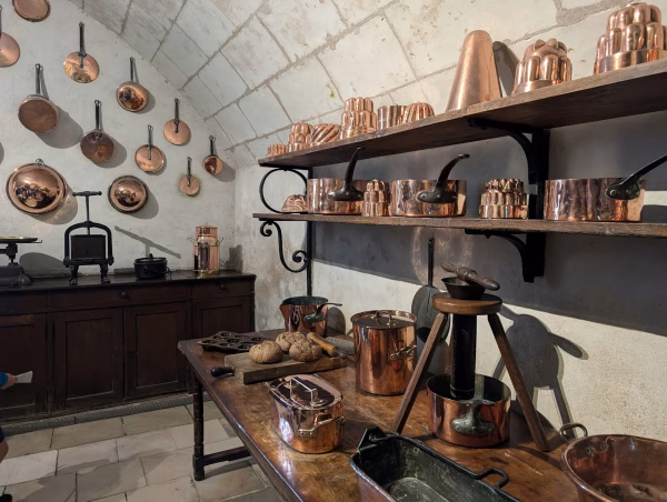 Homepage 10 explore sacramento A historic kitchen lined with polished copper pots, pans, and fluted copper molds on wooden shelves and whitewashed stone walls