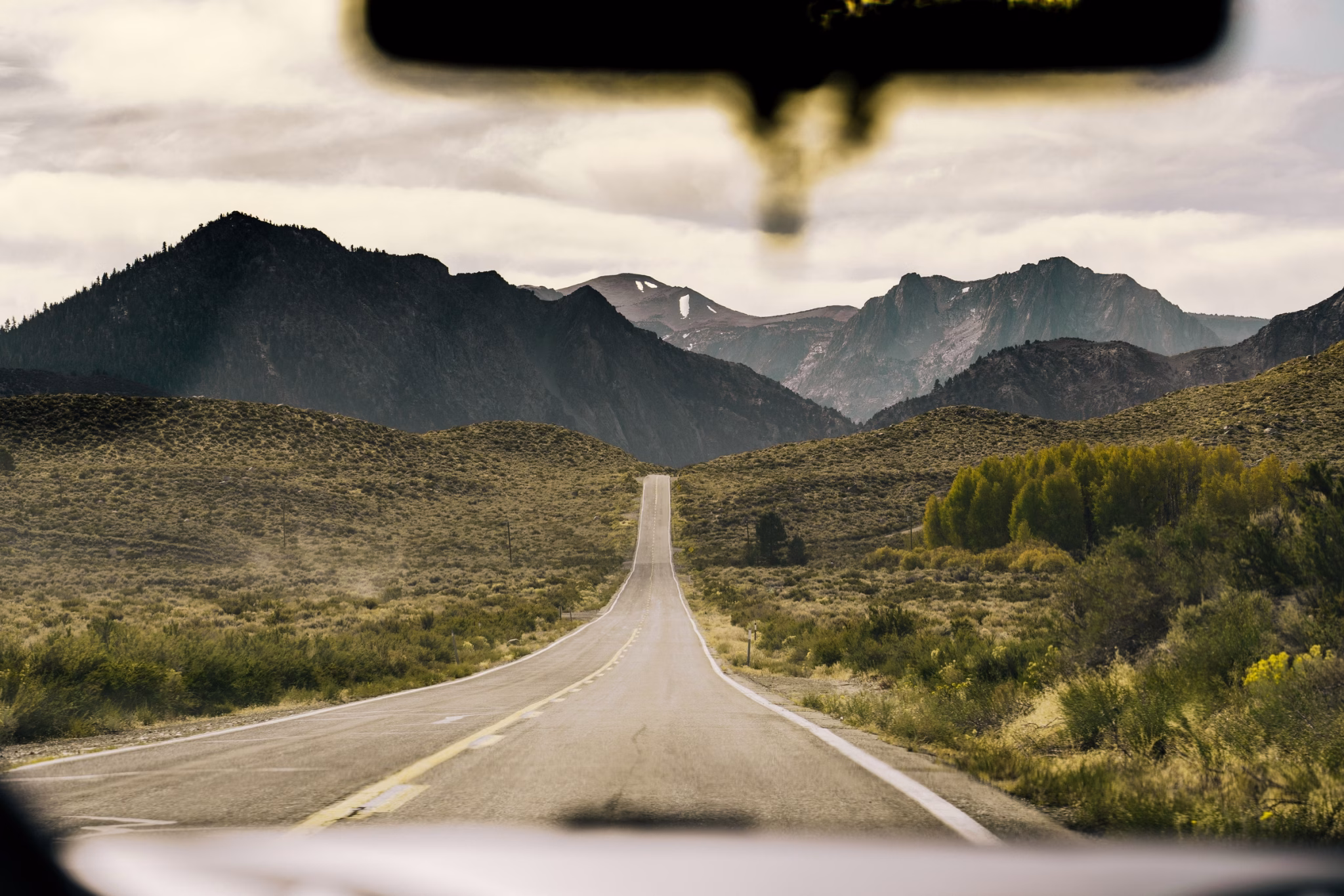 An open california highway heading toward the sierra nevada, seen through a car windshield