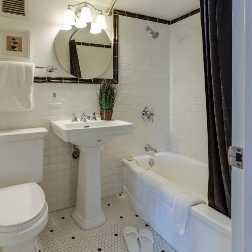 White subway tile bathroom with bathtub drain that was unclogged using enzyme drain cleaner