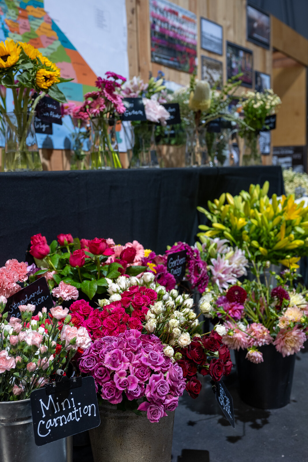 Buckets of california grown cut flowers beside a colorful map of california at the state fair floral exhibit