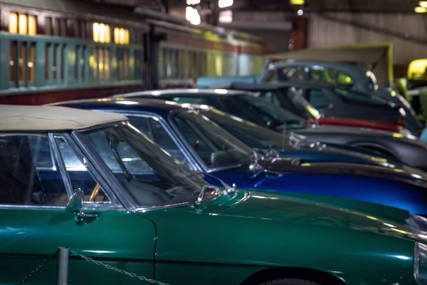 Row of classic cars lined up on the floor of an automobile museum