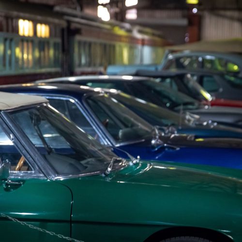 Row of classic cars lined up on the floor of an automobile museum