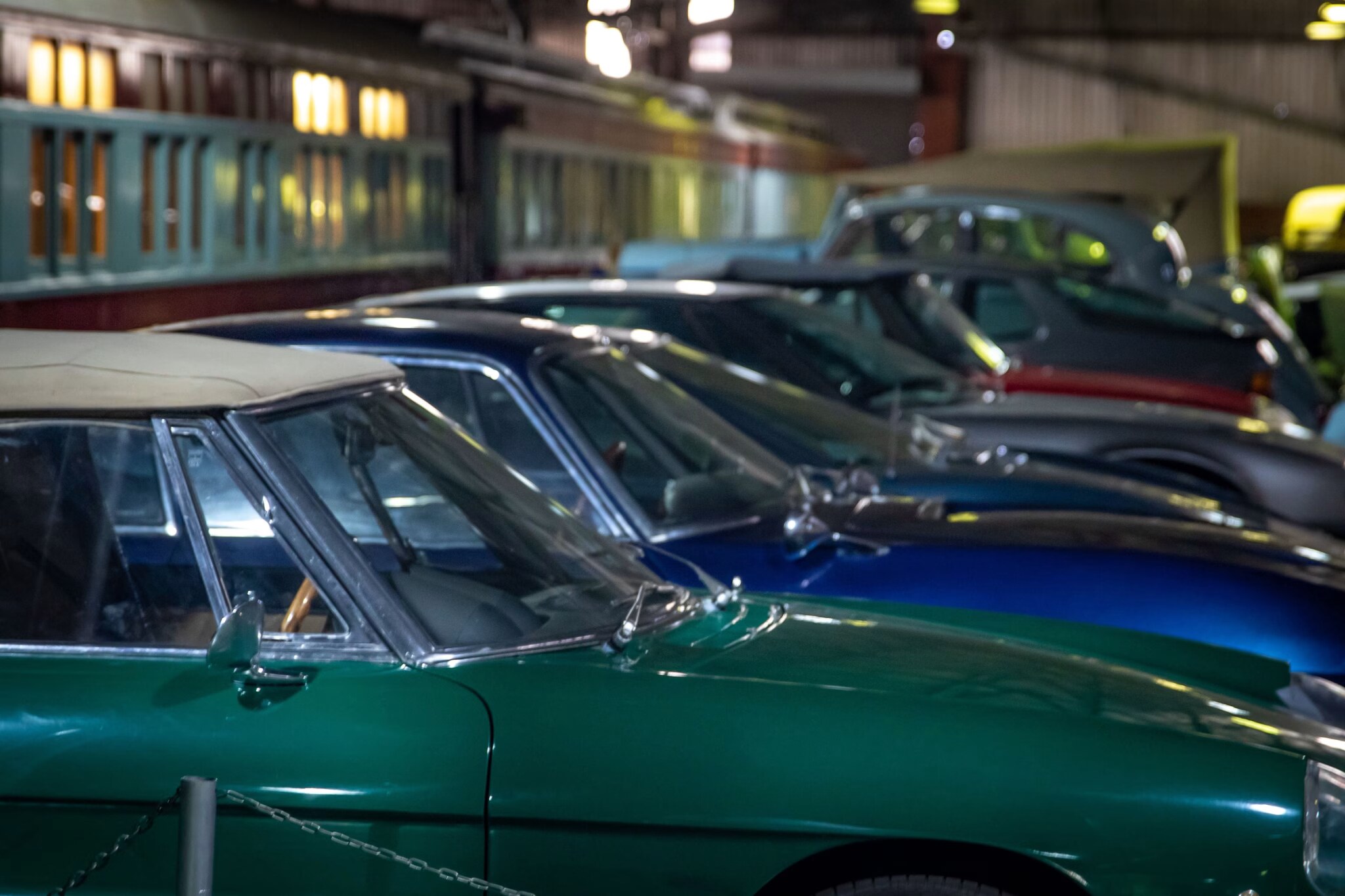 Row of classic cars lined up on the floor of an automobile museum