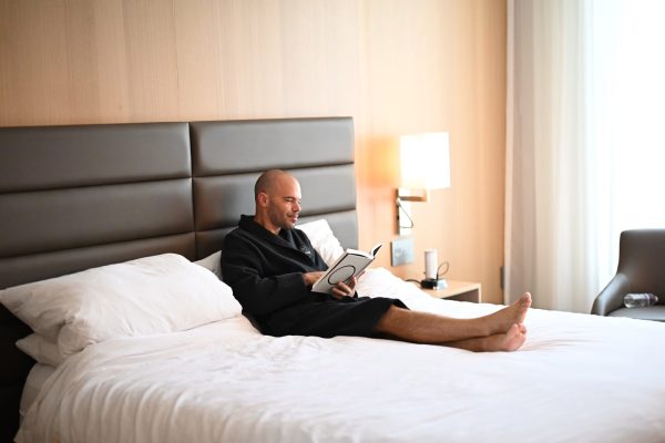 Michael kahn in a hotel robe, sitting up in bed reading a book, the same kind of sick-day research session that produced this probiotic-antibiotic guide