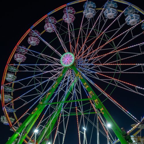 The giant ferris wheel lit up at night against a crescent moon at the california state fair