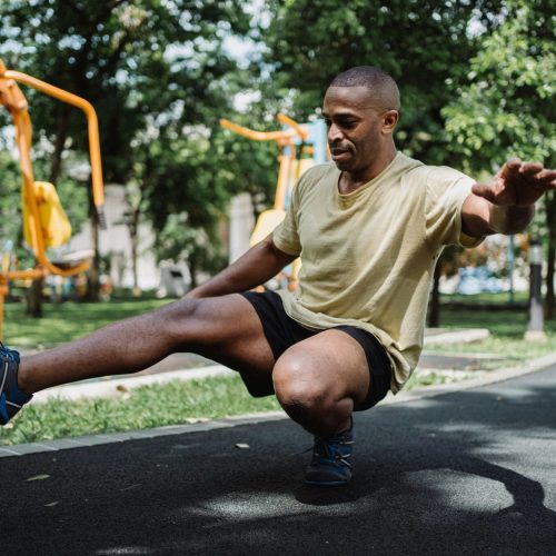 Athlete performing a single-leg balance exercise in an outdoor park, training for paddle board stability
