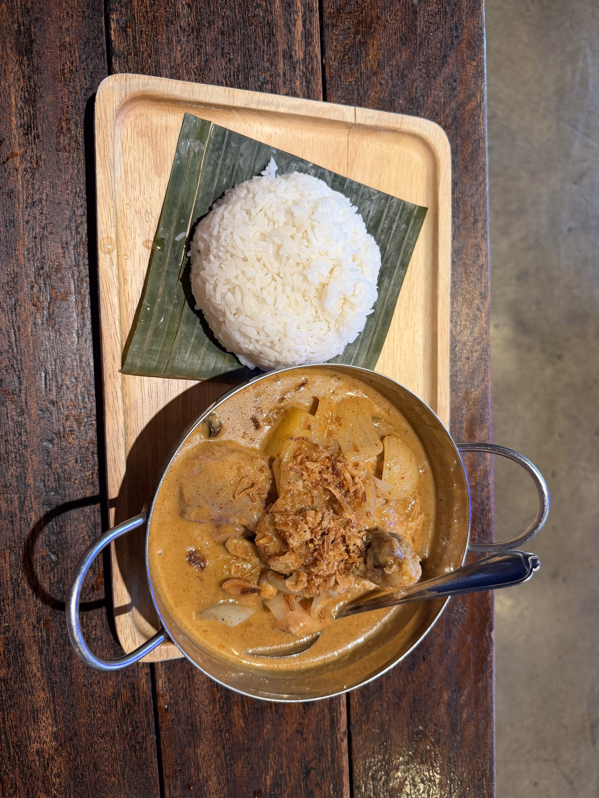 Massaman curry served in a metal pot beside jasmine rice on a banana leaf at kin thai street eatery
