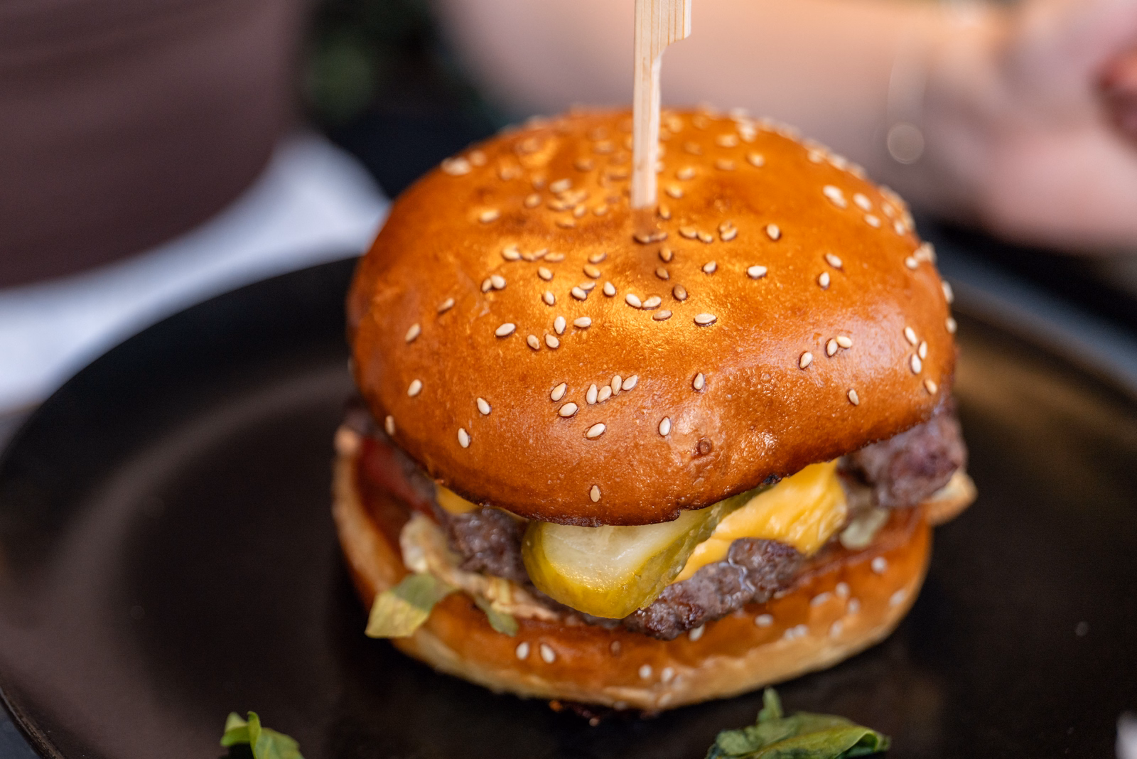 Cheeseburger with pickles on a dark plate