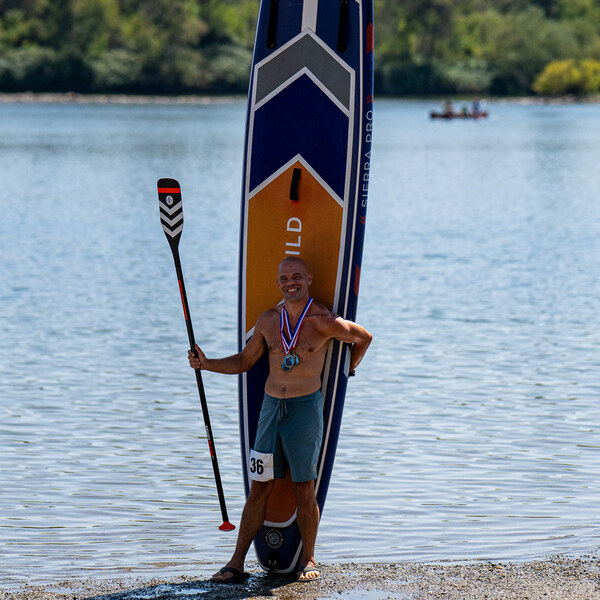 Michael Kahn wearing race medals beside his Sierra Pro inflatable board at Lake Natoma