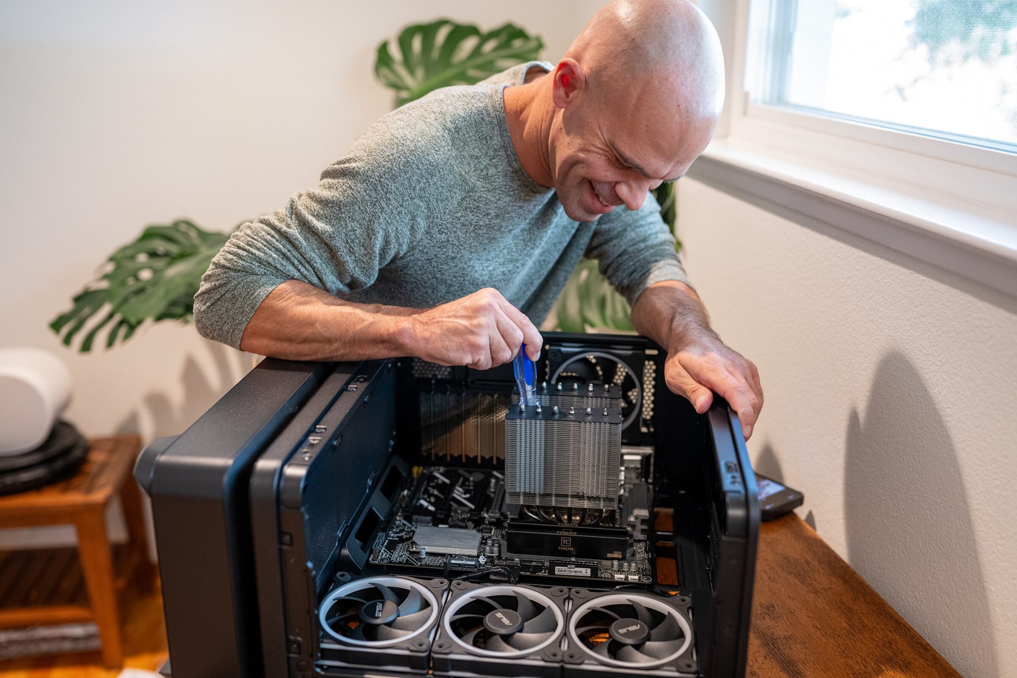 Michael kahn smiles as he screws a thermalright dual-tower heatsink onto the motherboard inside an asus prime ap304 case lying on its side