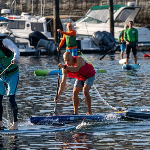 Michael kahn in a red race pinny hinging forward into a paddle stroke on an inflatable race board during a technical course heat at the 2026 usa sup national championships