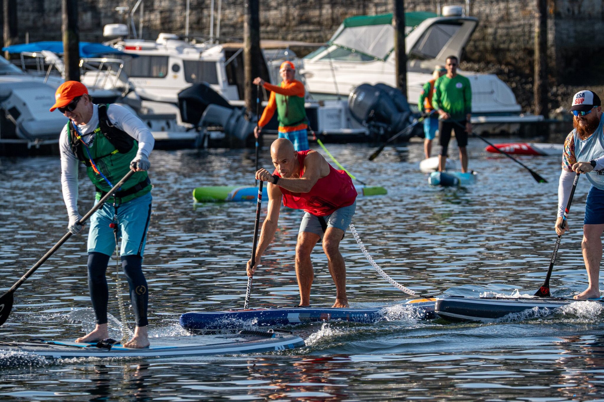 Michael kahn in a red race pinny hinging forward into a paddle stroke on an inflatable race board during a technical course heat at the 2026 usa sup national championships